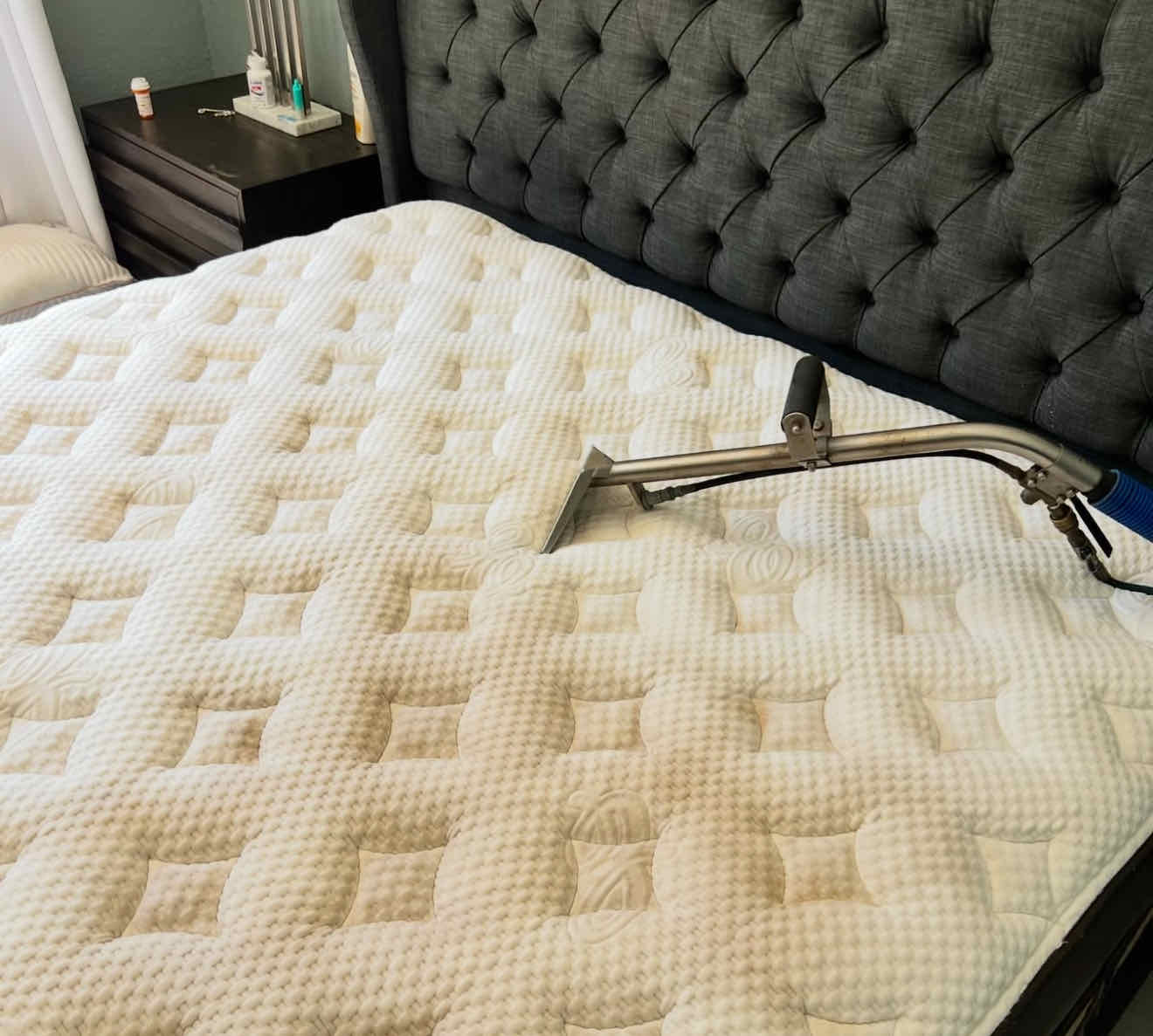 Steam wand deep-cleaning a quilted mattress