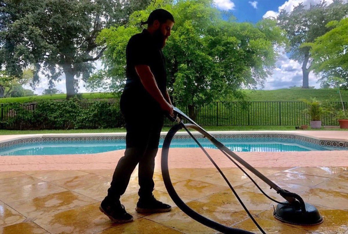 Technician pressure washing a stamped pool deck