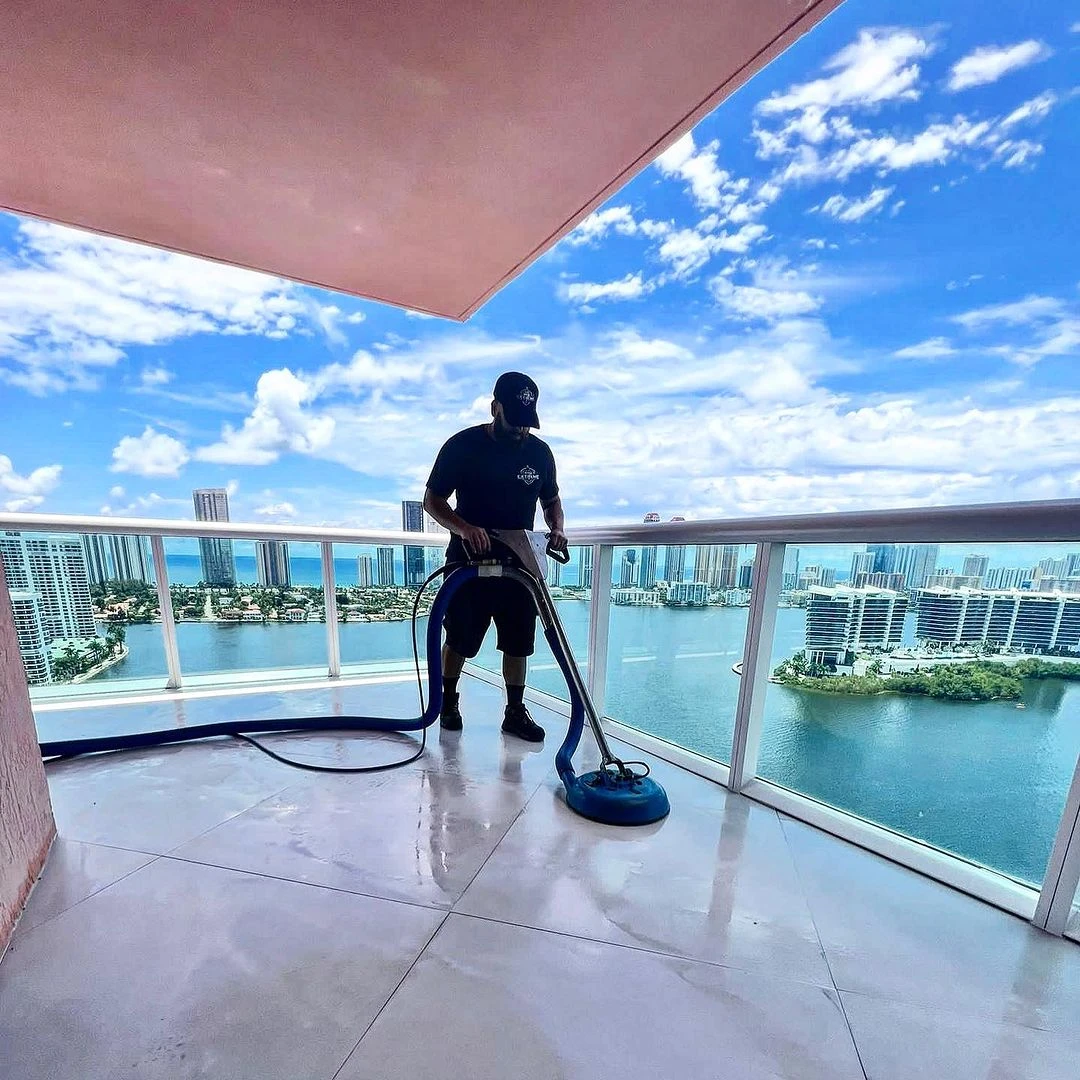 Technician steam-cleaning a high-rise balcony tile floor